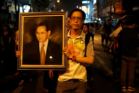 A man poses with a portrait of Thailand's King Bhumibol Adulyadej, as others line up to hold the portrait, after the announcement of the king's death, outside Siriraj hospital in Bangkok, Thailand October 13, 2016. REUTERS/Jorge Silva