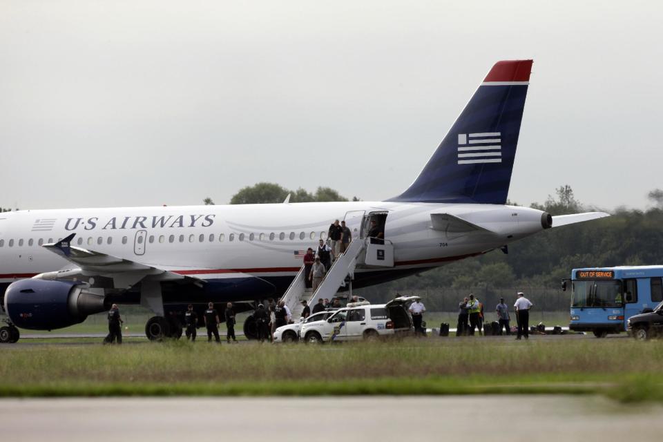 Passengers walk off a US Airways flight at Philadelphia International Airport, after the plane returned to the airport, Thursday, Sept. 6, 2012, in Philadelphia. Airport spokeswoman Victoria Lupica says US Airways Flight 1267 returned to the airport Thursday morning as a "precaution." Footage from WCAU-TV showed a person being escorted off the plane by law enforcement officials and police dogs on the tarmac. An FBI spokesman did not immediately comment on the situation.(AP Photo/Matt Rourke)