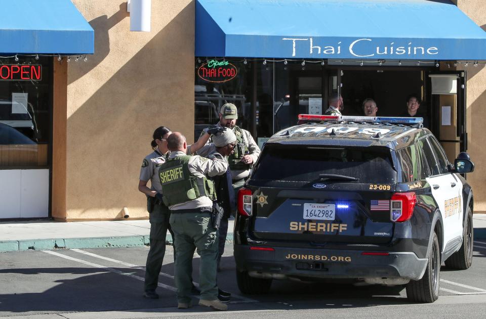 Riverside County sheriff's deputies search a woman before putting her in a cruiser Monday. The woman had been with a man who'd called police, then stabbed himself in the rear of the Starbucks at Highway 111 and Monterey Avenue in Palm Desert.