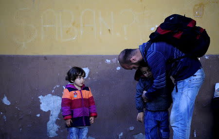 A migrant from Syria carries his child at Demirkapija train station in Macedonia June 17, 2015. REUTERS/Ognen Teofilovski