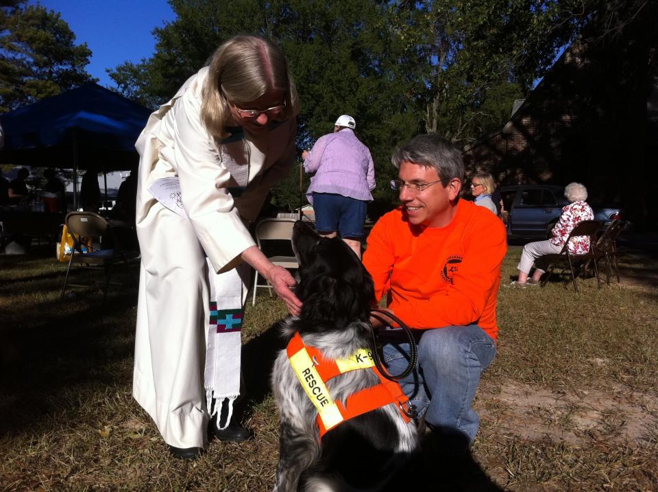 Jessie, one of the search and rescue dogs who is also participating in the ovarian cancer screening trial, being blessed by a local priest.