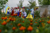 Children in traditional Ukrainian clothing run through a field after recording an online video message for the country's upcoming Independence Day on Aug. 24 at a community center in Andriivka, Donetsk region, eastern Ukraine, Friday, Aug. 19, 2022. (AP Photo/David Goldman)