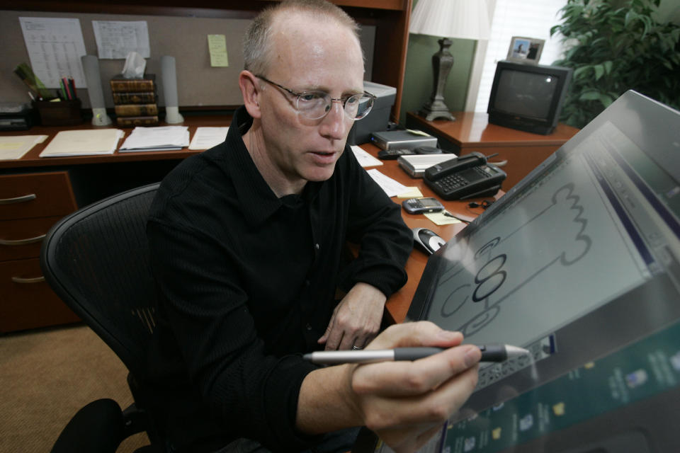 FILE - Scott Adams, creator of Dilbert, works on his comic strip in his studio in in Dublin, Calif., on Oct. 26, 2006. Syndication company Andrews McMeel announced they were severing ties with Adams after he made comments about race on his YouTube show, “Real Coffee with Scott Adams.” (AP Photo/Marcio Jose Sanchez, File)