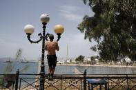 A man trains on a lighting column during a warm day in Piraeus, near Athens, Wednesday, May 20, 2020. Public beaches were reopened last weekend amid heatwave temperatures, with strict distancing rules imposed by the government, but crowding did occur on buses from Athens to the nearby coast. Travel to the Greek islands remains broadly restricted due to the coronavirus pandemic. (AP Photo/Thanassis Stavrakis)