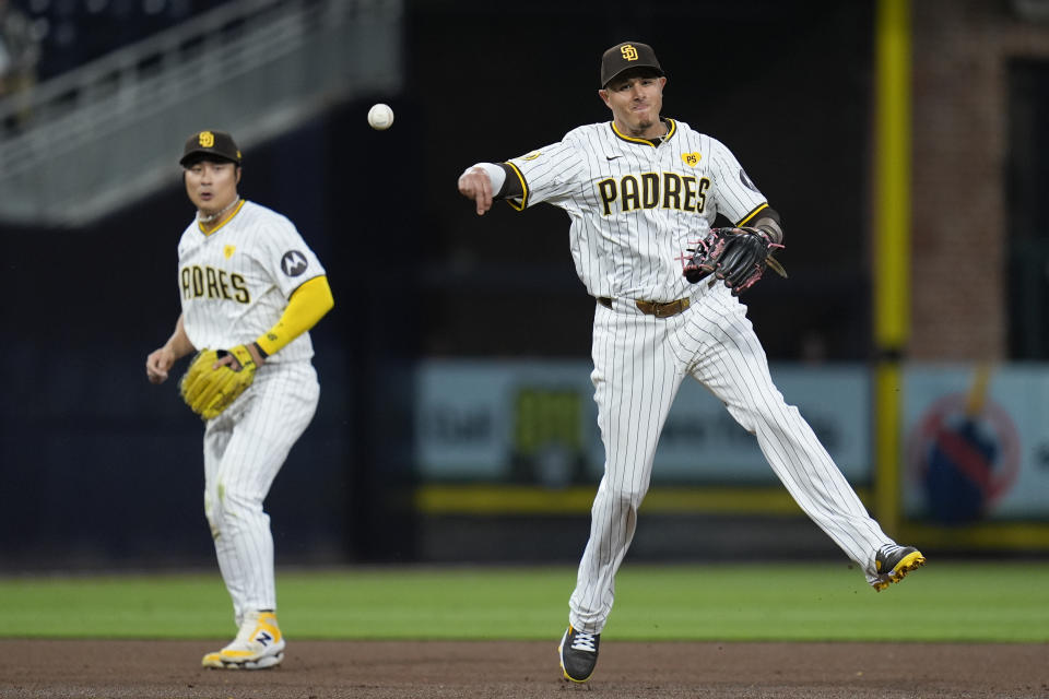 San Diego Padres third baseman Manny Machado, right, throws to first for the out on Colorado Rockies' Brenton Doyle as San Diego Padres shortstop Ha-Seong Kim looks on during the fifth inning of a baseball game, Monday, May 13, 2024, in San Diego. (AP Photo/Gregory Bull)