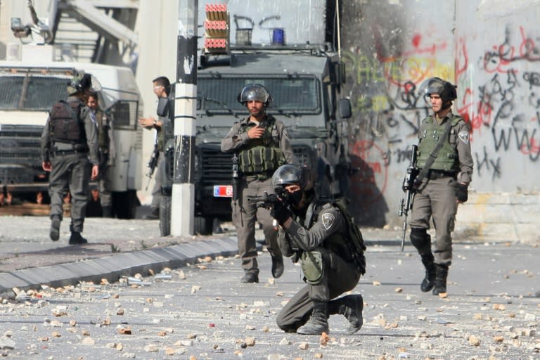 An Israeli border guard aims his weapon at Palestinian stone throwers during clashes at the main entrance of the West Bank town of Bethlehem on October 6, 2015