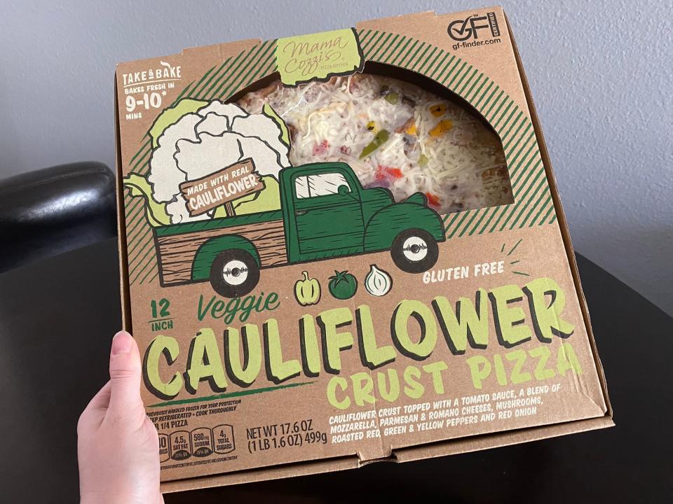 The writer holds a box of Mama Cozzi's cauliflower-crust pizza