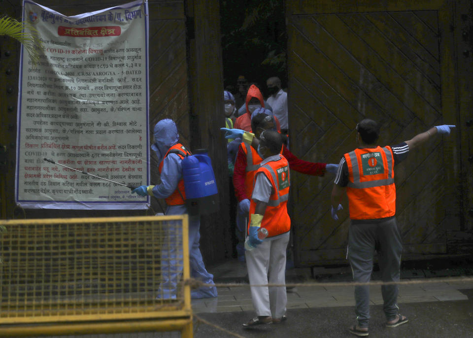 Civic workers sanitize the entrance of Bollywood superstar Amitabh Bachchan's residence after Bachchan and his son tested positive for the coronavirus and were hospitalized in Mumbai, India, Sunday, July 12, 2020. (AP Photo/Rafiq Maqbool)