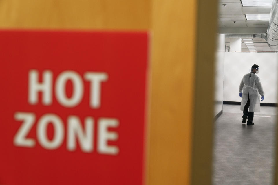 FILE - In this Dec. 1, 2020, file photo, a worker walks through the hallway of a newly opened field hospital operated by Care New England to handle a surge of COVID-19 patients in Cranston, R.I. States faced a deadline on Friday, Dec. 4, 2020, to place orders for the coronavirus vaccine as many reported record infections, hospitalizations and deaths, while hospitals were pushed to the breaking point — with the worst feared yet to come. (AP Photo/David Goldman, File)