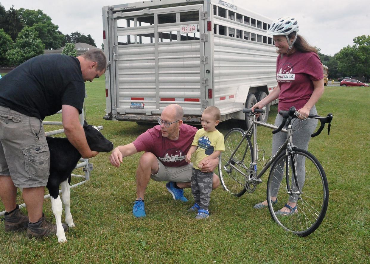 Jarrod Snell holds onto a three-day-old calf so Steve and Elliot Lyon and Elizabeth Schuster, co-chair of the event, can take a look at it. The stop was located on the path around the soccer fields on the north end of Wooster for the 2021 Run, Walk and Roll scavenger hunt event. This year's event is June 18.