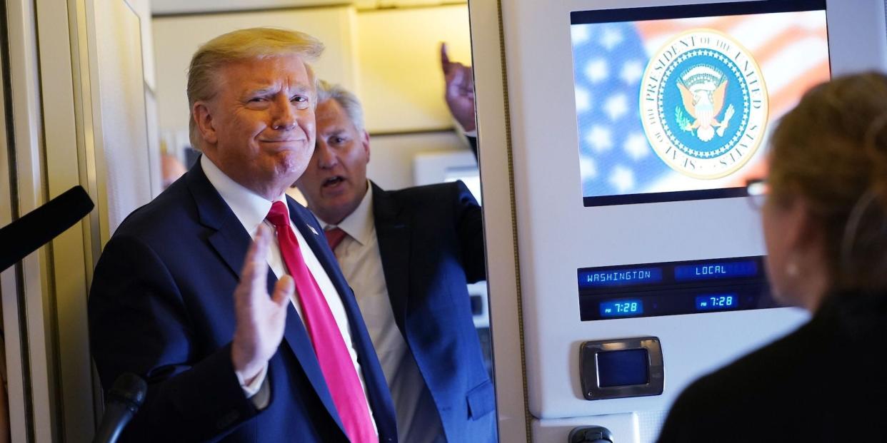 Then-US President Donald Trump, his right hand raised to should level as if in mid-salute, addresses the traveling press pool as House Minority Leader Kevin McCarthy, who is behind him, tries to chime in.