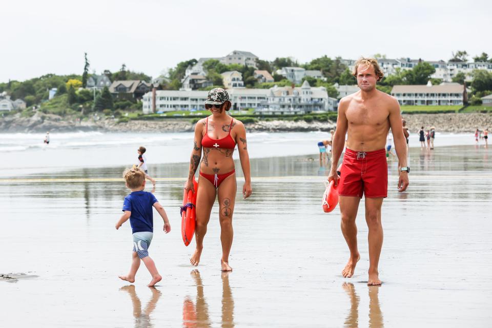 A young beachgoer crosses paths with Ogunquit Beach lifeguards Alma Hollowell and Colby Lapointe while on patrol in Maine.