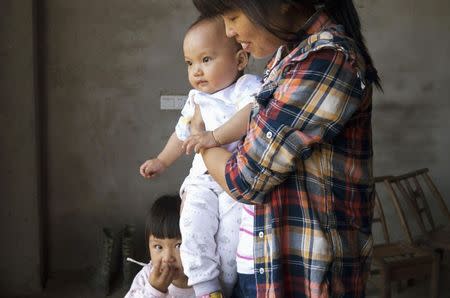 Liu Guimei holds her grandson, Xu Ning, next to granddaughter Xu Yilin, whose blood, according to her family, has been shown to have almost three times the national limit for lead exposure in children, in Dapu town, Hunan province, June 25, 2014. REUTERS/Alexandra Harney