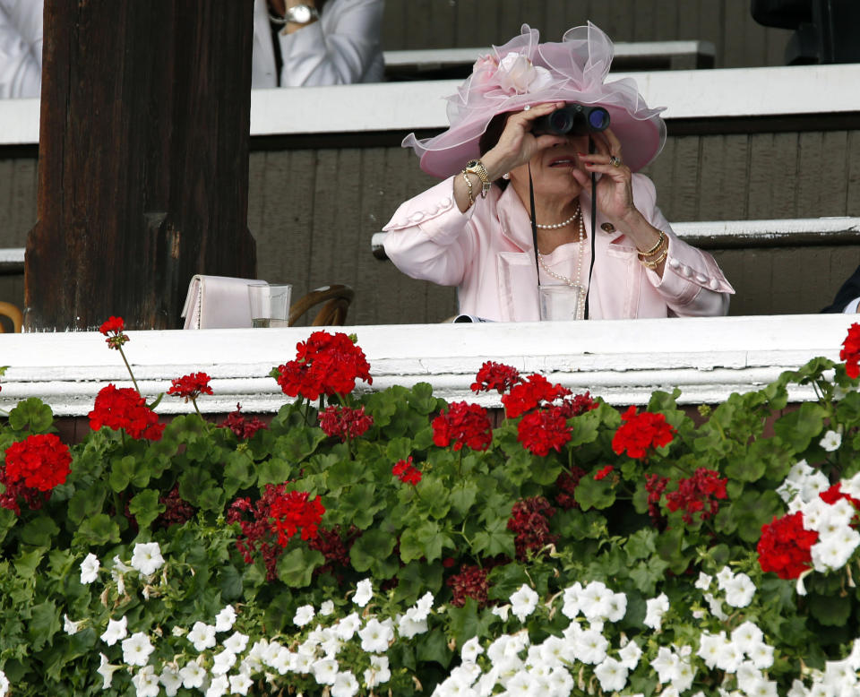 FILE - In this July 20, 2012 file photo, a woman watches the fifth horse race on opening day at Saratoga Race Course in Saratoga Springs, N.Y. Saratoga Springs' racetrack is still going strong as it marks its 150th anniversary this summer, the centerpiece attraction in a town that's also known for mineral springs, Victorian charm and upscale hotels, shops and restaurants. (AP Photo/Mike Groll, File)