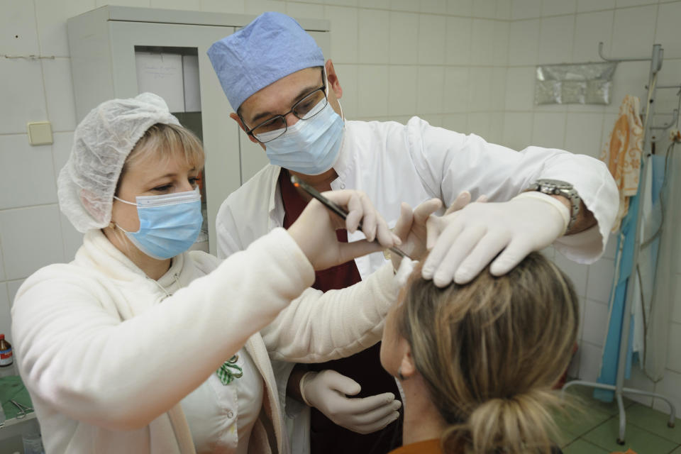 Ukrainian doctor Oleh Duda, centre, examines a patient at the hospital in western city of Lviv, Ukraine, on Saturday, Nov. 26, 2022. Russia's devastating strikes on Ukraine's power grid have strained and disrupted the country’s health care system, already battered by years of corruption, mismanagement, the COVID-19 pandemic and nine months of war. (AP Photo/Mykola Tys)