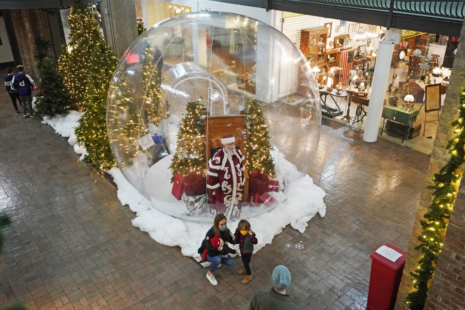 Father Frost looks through decorated 10-foot snow globe at Trolley Square in Salt Lake City on Dec. 10, 2020. In this socially distant holiday season, Santa Claus is still coming to towns (and shopping malls) across America but with a few 2020 rules in effect. (AP Photo/Rick Bowmer)