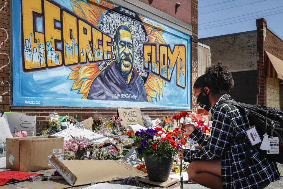 Malaysia Hammond places flowers at a memorial mural for George Floyd at the corner of Chicago Avenue and 38th Street in Minneapolis on May 31, 2020.