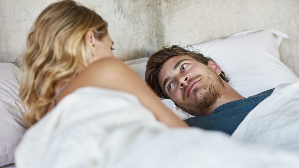 loving young man looking at woman in bed