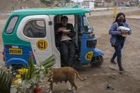 A man eats lunch in a motorcycle taxi outside a cemetery at Villa el Salvador on the outskirts of Lima, Peru, Tuesday, June 30, 2020. (AP Photo/Rodrigo Abd)