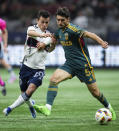 Vancouver Whitecaps' Andres Cubas, left, and LA Galaxy's Gaston Brugman vie for the ball during the second half of an MLS soccer match Saturday, April 13, 2024, in Vancouver, British Columbia. (Darryl Dyck/The Canadian Press via AP)