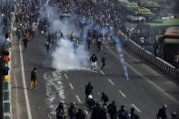 NEW DELHI, INDIA - JANUARY 26: Demonstrators being tear gassed by police at NH-24 near Akshardham during the farmers' tractor rally on Republic Day, on January 26, 2021 in New Delhi, India. Major scenes of chaos and mayhem at Delhi borders as groups of farmers allegedly broke barricades and police check posts and entered the national capital before permitted timings. Police used tear gas at Delhi's Mukarba Chowk to bring the groups under control. Clashes were also reported at ITO, Akshardham. Several rounds of talks between the government and protesting farmers have failed to resolve the impasse over the three farm laws. The kisan bodies, which have been protesting in the national capital for almost two months, demanding the repeal of three contentious farm laws have remained firm on their decision to hold a tractor rally on the occasion of Republic Day.(Photo by Sanjeev Verma/Hindustan Times via Getty Images)