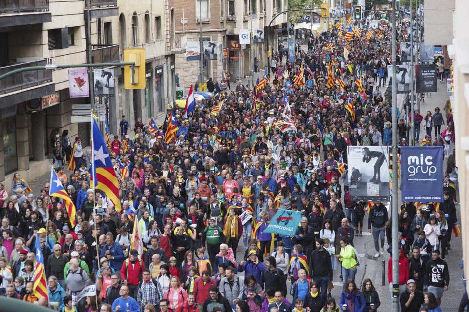 Demonstrators a long a street in Girona, Spain, Wednesday, Oct. 16, 2019. Thousands of people have joined five large protest marches across Catalonia that are set to converge on Barcelona, as the restive region reels from two straight days of violent clashes between police and protesters. The marches set off from several Catalan towns and aimed to reach the Catalan capital by Friday. (AP Photo/Mar Grau)
