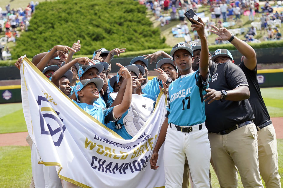 Curacao pitcher Helmir Helmijr (17) takes a selfie with the team and the championship banner after their 2-0 win against Taiwan during the International Championship baseball game at the Little League World Series tournament in South Williamsport, Pa., Saturday, Aug. 26, 2023. (AP Photo/Tom E. Puskar)