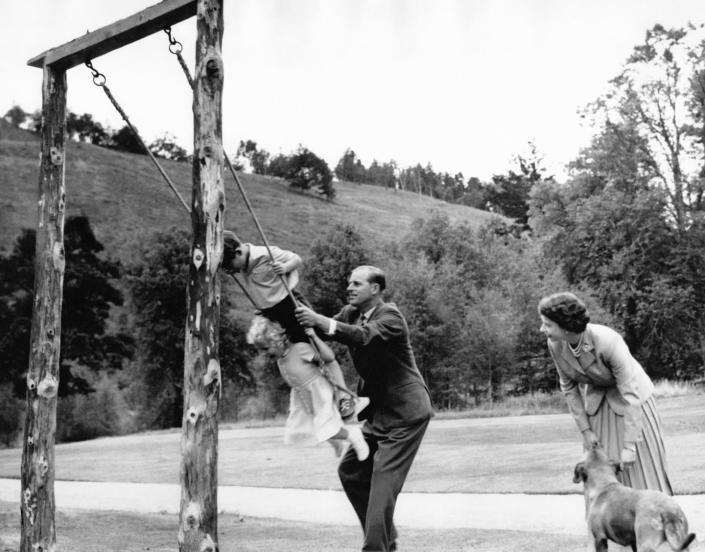 <p>Prince Philip pushes Prince Charles and Princess Anne on a swing at Balmoral, while the Queen and a dog watch on.</p>