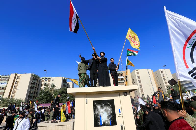 Protesters and militia fighters gather to condemn air strikes on bases belonging to Hashd al-Shaabi, outside the main gate of the U.S. Embassy in Baghdad