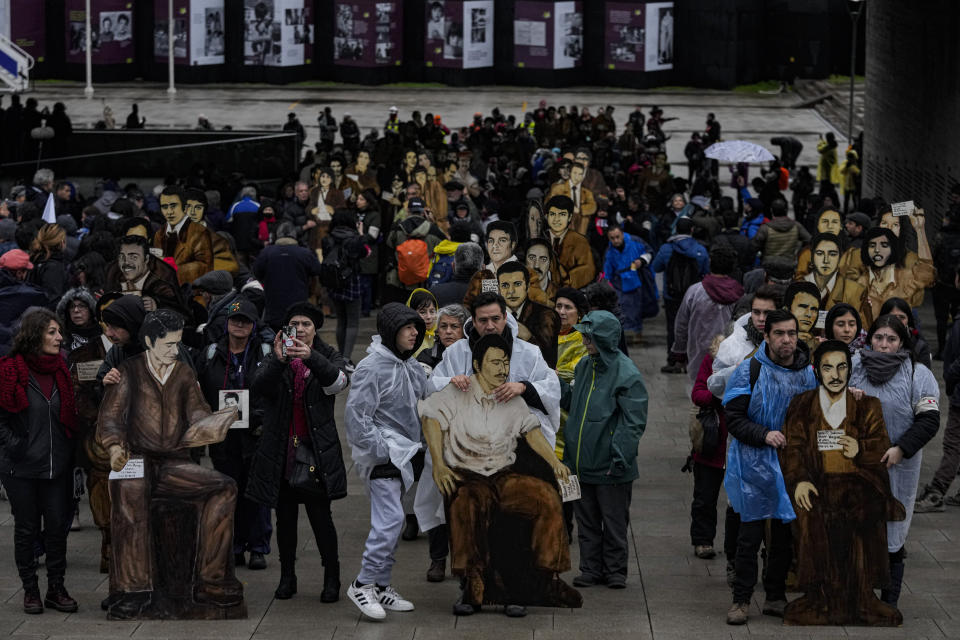 Miembros de la Agrupación de Familiares de Detenidos Desaparecidos se desplazan con siluetas de cartón que describen a sus parientes desaparecidos durante una marcha en Santiago, Chile, el sábado 22 de julio de 2023, para conmemorar a las víctimas de la llamada Operación Colombia en la que más de cien disidentes fueron ejecutados por las fuerzas de seguridad durante la dictadura de Augusto Pinochet. (AP Foto/Esteban Felix)