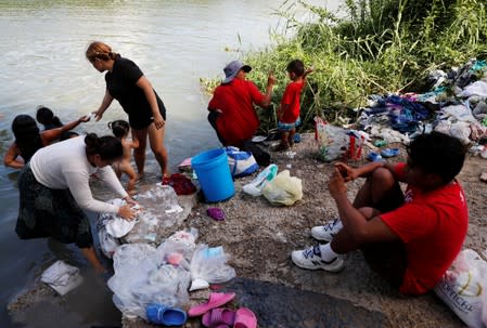 Central American migrants wash their clothes in the Rio Bravo near an encampment in Matamoros
