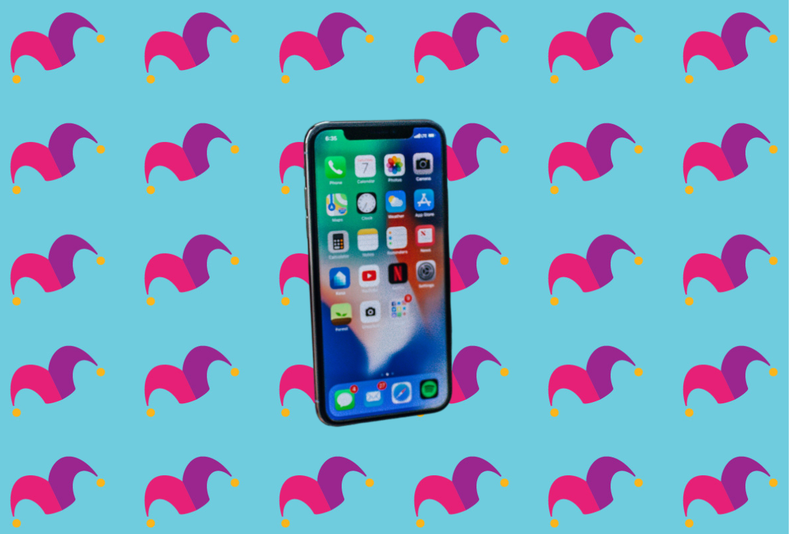 A cell phone on top of a multicolored background covered in jester caps
