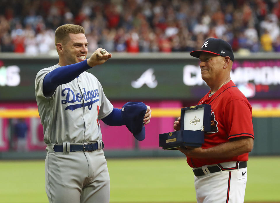 Atlanta Braves manager Brian Snitker, right, presents former Braves first baseman Freddie Freeman with his World Series Championship ring and Freeman displays it to fans during his return to Atlanta with the Los Angles Dodgers for a baseball game Friday, June 24, 2022, in Atlanta. (Curtis Compton/Atlanta Journal-Constitution via AP)