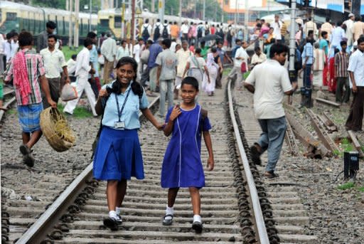 Indian school girls walk on the tracks as passengers wait near the platform of Sealdah train station for the resumption of services during a power failure in Kolkata