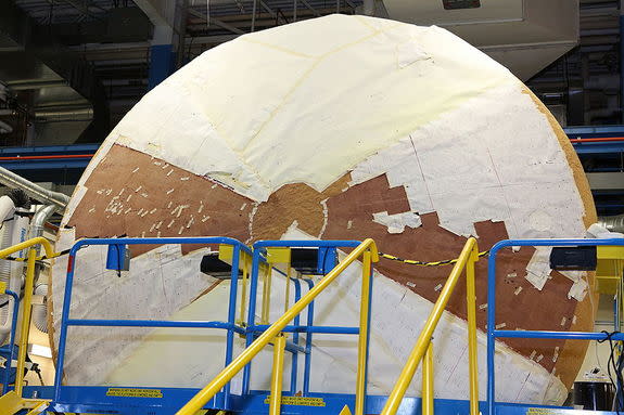The heat shield for NASA’s Orion Multi-Purpose Crew Vehicle, shown here partly wrapped and mounted on its side, is being coated with a layer of thermal protection material at the Textron Defense Systems plant in Wilmington, Mass. It is the worl