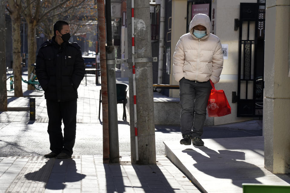 Residents wearing masks walk on the street of Beijing, Friday, Dec. 16, 2022. A week after China dramatically eased some of the world's strictest COVID-19 containment measures, uncertainty remained Thursday over the direction of the pandemic in the world's most populous nation. (AP Photo/Ng Han Guan)