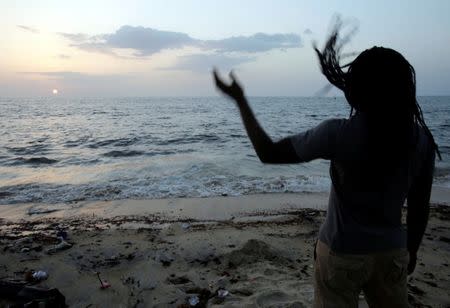 A man watches the setting sun on the beach in the township of West Point, in Monrovia, Liberia, October 18, 2017. REUTERS/Thierry Gouegnon