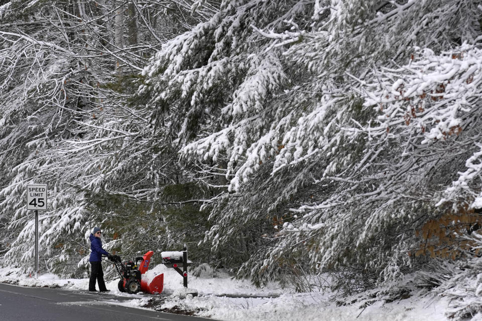 Meghan Hall clears snow from her driveway following a winter storm, Wednesday, March 15, 2023, in Poland, Maine. The storm dumped heavy, wet snow on parts of the Northeast, causing tens of thousands of power outages. (AP Photo/Robert F. Bukaty)