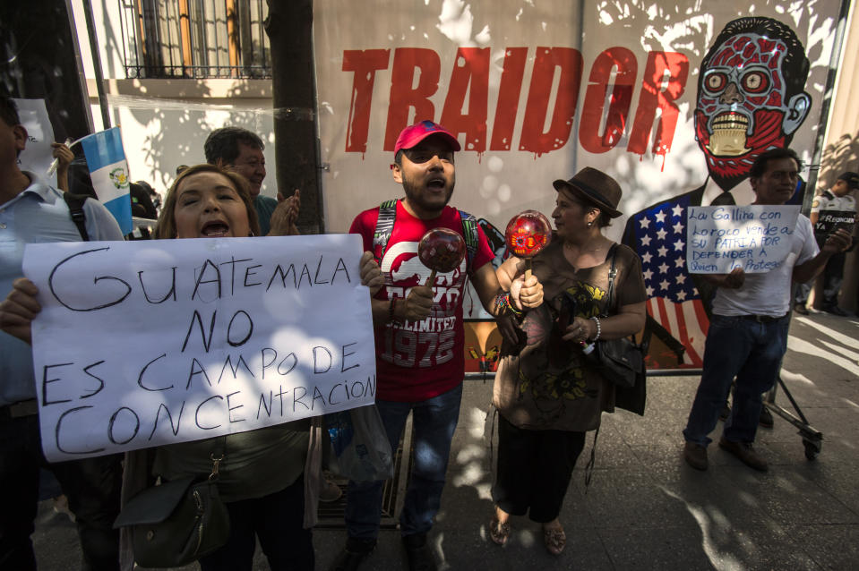 Demonstrators protest their government's agreement with Washington to require migrants passing through Guatemala to seek asylum there, rather than pushing on to the U.S., outside the Presidential House in Guatemala City, Saturday, July 27, 2019. The signs read in Spanish "Guatemala is not a concentration camp," left, and "Traitor," top. (AP Photo/Oliver de Ros)