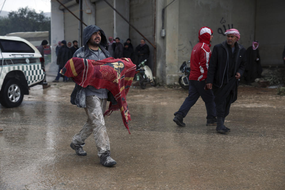 A man carries the body of an earthquake victim in the Besnia village near the Turkish border, Idlib province, Syria, Monday, Feb. 6, 2023. A powerful earthquake has caused significant damage in southeast Turkey and Syria and many casualties are feared. Damage was reported across several Turkish provinces, and rescue teams were being sent from around the country. (AP Photo/Ghaith Alsayed)