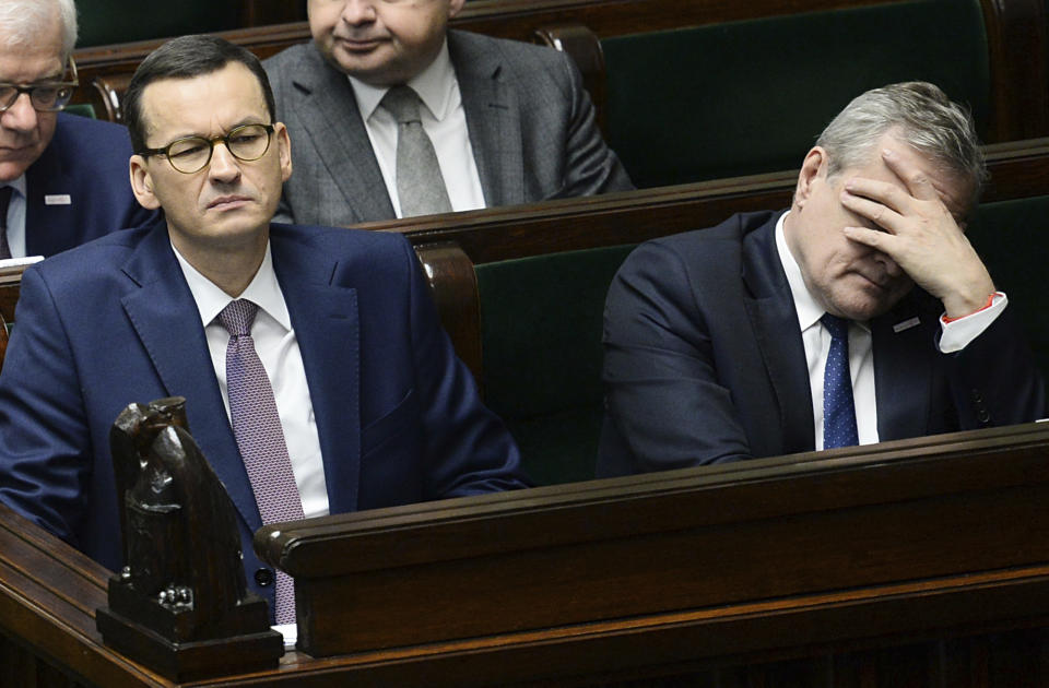 Polish Prime Minister Mateusz Morawiecki, left, and his deputy, Minister of Culture Piotr Glinski listen to a parliamentary debate after Morawiecki called for a confidence vote in his government, saying he wants to be sure that his government has a mandate ahead of the European Union summit, in Warsaw, Poland, Wednesday, Dec. 12, 2018. (AP Photo/Alik Keplicz)