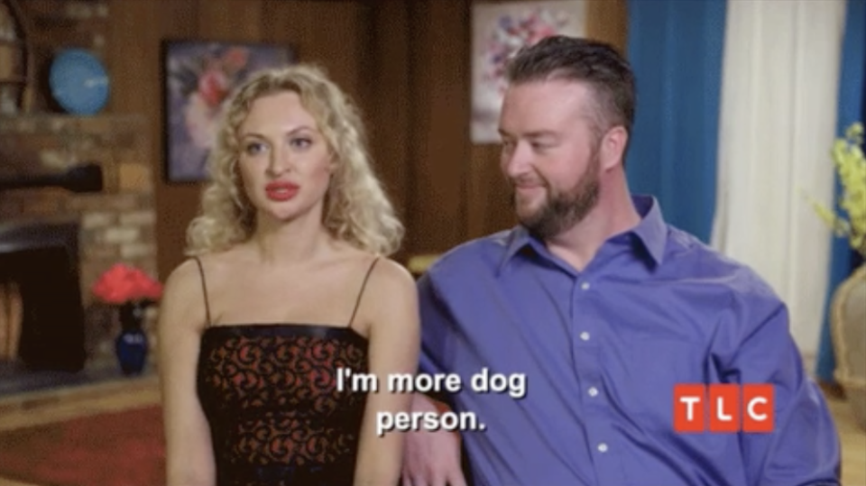 A woman sits next to her fiancé ad says "I'm more dog person"