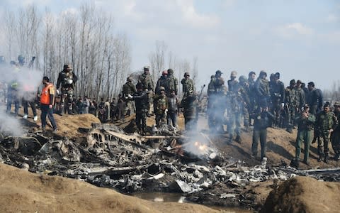 Indian soldiers and Kashmiri onlookers stand near the remains of an Indian Air Force helicopter after it crashed in Budgam district - Credit: Tauseef Mustafa/AFP