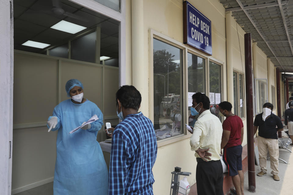 People wait in a queue to interact with their relatives through a video phone facility set up by a COVID- 19 help desk outside a hospital, in New Delhi, India, Friday, July 3, 2020. India's number of coronavirus cases passed 600,000 on Thursday with the nation's infection curve rising and its testing capacity being increased. More than 60% of the cases are in the worst-hit Maharashtra state, Tamil Nadu state, and the capital territory of New Delhi. (AP Photo/Manish Swarup)