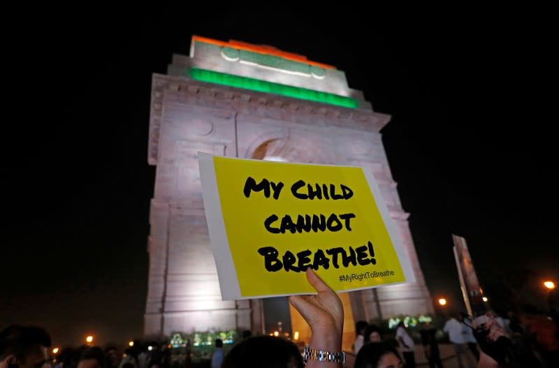 FILE PHOTO: A protestor holds a placard in front of the India Gate during a protest demanding government to take immediate steps to control air pollution in New Delhi