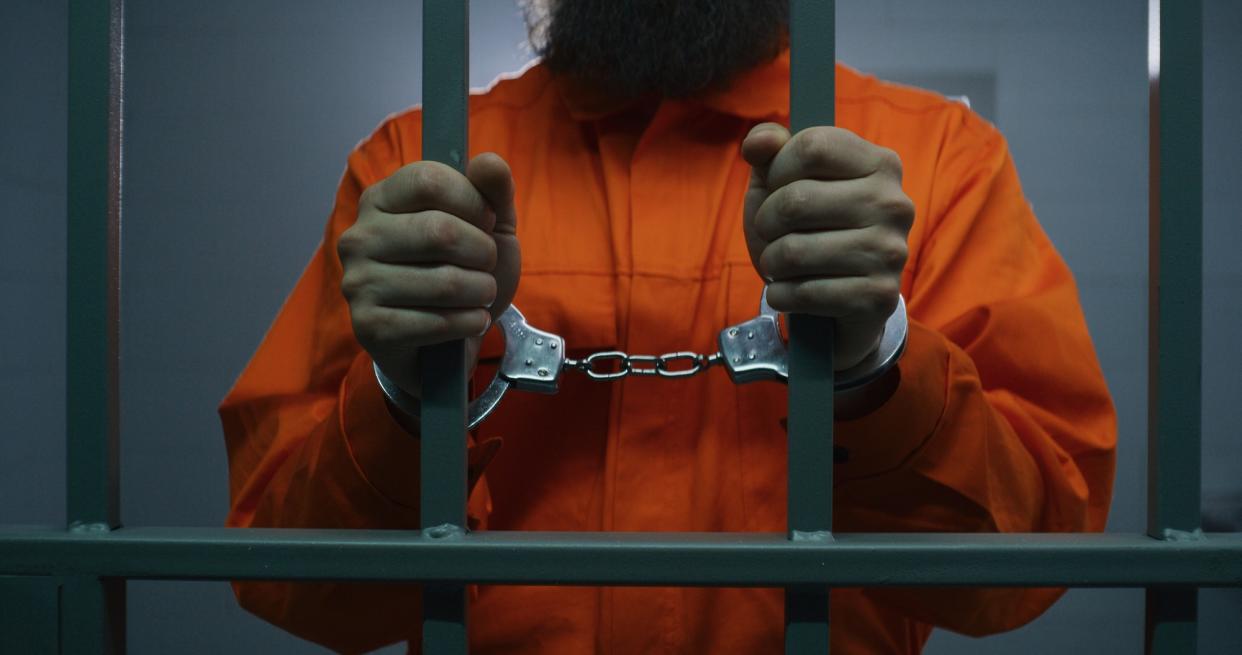  Twisted Cover Up airs Saturday, May 25 on Investigation Discovery. Pictured: Criminal in orange uniform and handcuffs holds metal bars, stands in prison cell,. 