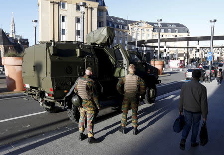 Belgian soldiers stand next to a military armoured vehicle as they patrol in central Brussels, December 31, 2015. REUTERS/Francois Lenoir