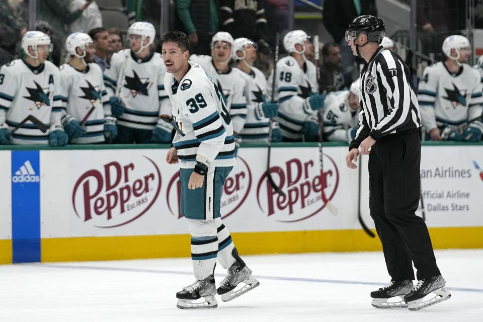 San Jose Sharks center Logan Couture (39) is escorted off the ice by linesman Caleb Apperson (77) in the final minutes of the second period of an NHL hockey game against the Dallas Stars after being issued a penalty for fighting in Dallas, Friday, Nov. 11, 2022. (AP Photo/Tony Gutierrez)