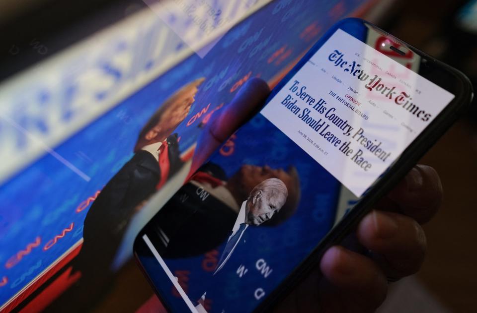 This illustration photo created on June 28, 2024 in Los Angeles, shows the New York Times editorial calling for President Joe Biden to leave the presidential race on a smartphone screen next to a screen showing a photo of former President Donald Trump during the June 27 presidential debate. America's most influential newspaper, The New York Times, called in an editorial on June 28 for President Joe Biden to step aside and allow another Democrat to challenge Donald Trump for the White House in November. Describing Biden as "the shadow of a great public servant," the newspaper's editorial board -- which is separate from its newsroom -- said Thursday's debate between the president and Trump proved the 81-year-old "failed his own test." (Photo by Chris DELMAS / AFP) (Photo by CHRIS DELMAS/AFP via Getty Images)