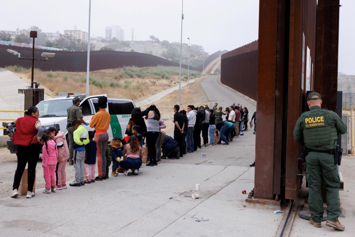 <span>US border patrol agents sort people who gathered between the primary and secondary border walls that separate Mexico and the US in San Diego, California, on 6 June 2024.</span><span>Photograph: Mike Blake/Reuters</span>